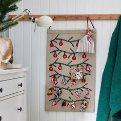 a christmas tree is hanging on the wall next to a white dresser and green towel