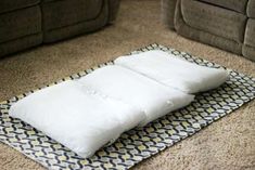 two pillows sitting on top of a mat in the middle of a living room floor