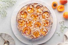 an orange cake with powdered sugar on top and fresh apricots in the background