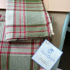 a plaid blanket with a tag on it next to a laptop computer and other items