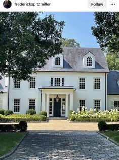 a large white house with lots of windows on it's front door and driveway