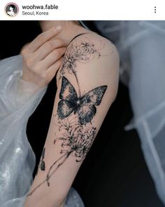 a woman's arm with a butterfly and flowers tattoo on the left side of her arm