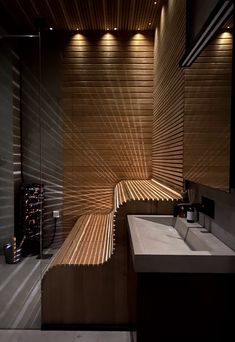 a modern bathroom with wooden slats on the walls and flooring, along with two sinks