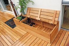 a wooden bench sitting on top of a wooden floor next to a potted plant