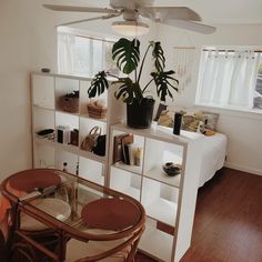 a living room with a table, fan and shelves filled with books on top of it