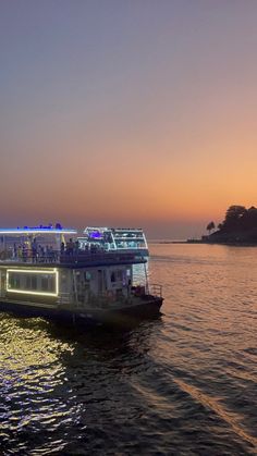 a boat with people on it is floating in the water at sunset or sunrise time