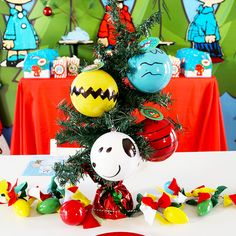 a decorated christmas tree with ornaments on it in front of a red table cloth covered wall