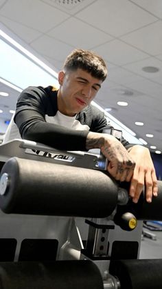 a man sitting on top of a machine in a gym with his hand resting on the arm