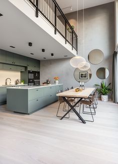 an open kitchen and dining room area in a modern home with wood floors, gray walls, and white ceilinging