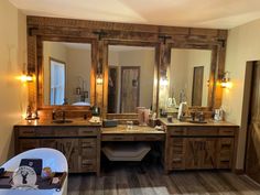 a bathroom with two sinks, mirrors and lights on the wall above it is also a bathtub