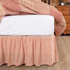 a bed with an orange and white striped bedspread on it's side