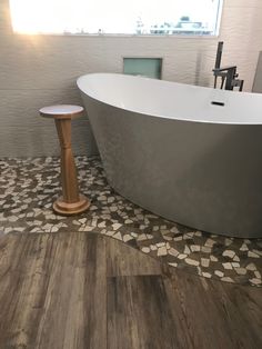 a bath tub sitting on top of a wooden floor next to a window in a bathroom