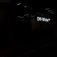 an off - white sign is lit up in the dark