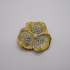 Vintage BSK signed goldtone pansy brooch with rhinestones surrounding a tiny pearl in the center. Gold Flower Brooches With Rhinestones, Vintage Gold Brooches With Rhinestones, Vintage Yellow Gold Flower Brooch, Gold Flower-shaped Brooch With Handmade Flowers, Gold Flower-shaped Brooch With Rhinestones, Gold Flower-shaped Brooches With Rhinestones, Vintage Gold Flower Shaped Brooch, Gold Flower-shaped Rhinestone Brooches, Pansies Flowers