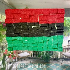 a flag made out of pieces of paper sitting on top of a porch next to chairs