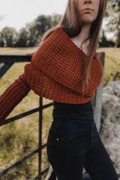 a woman leaning against a fence with her hands on her hips