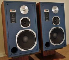 two speakers sitting side by side on top of a wooden stand