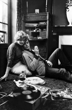 black and white photograph of two people sitting on the floor in front of a record player