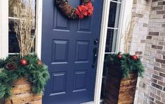 a blue front door with two wooden planters and a wreath on the side of it