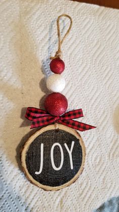 a christmas ornament hanging from a wooden slice with the word joy on it