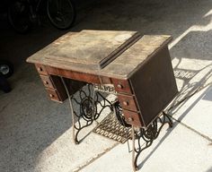 an old sewing table with wheels and drawers on it's legs is sitting on the sidewalk