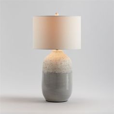 a gray and white table lamp with a beige shade