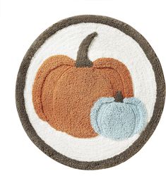 a rug with a pumpkin on it and a blue one in the middle, sitting on top of a white surface