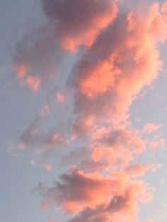 the airplane is flying high in the sky with pink and blue clouds above it at sunset