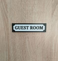 a sign that says guest room on the front of a wooden door with black lettering