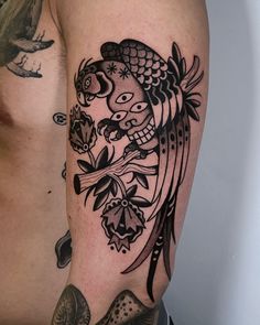 a man's arm with a bird and flowers tattoo on the left side of his body