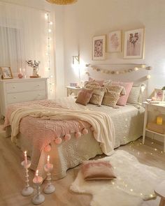 a bedroom decorated in pink and white with lights