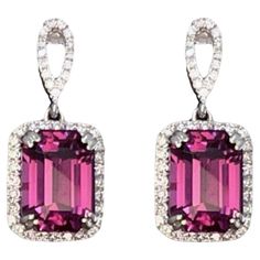 Experience the dazzling radiance of these Mahenge garnet drop earrings, adorned with stunning hints of neon pink, magenta and purple that will capture your attention from the very first glance. Boasting impressive clarity, cut, and color, these earrings outshine most other colored gemstones. The sizable stones, each weighing 3.27 carats each and have a total weight of 6.54Ct. They are elegantly set in 14K white gold and accentuated by a sparkling halo of 0.39 carats of round diamonds. Material: Emerald Cut Earrings, Garnet Drop Earrings, Garnet Color, Rose Violette, Pinkish Purple, Cut Earrings, Colored Gemstones, Purple Jewelry, Glasses Sunglasses