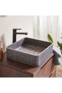 a bathroom sink sitting on top of a wooden counter next to a plant in a vase