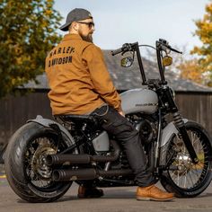 a man sitting on top of a motorcycle wearing a brown jacket and black pants with the words harley davidson written on it