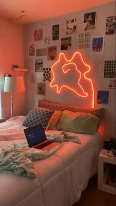 a laptop computer sitting on top of a white bed in a room with pink walls