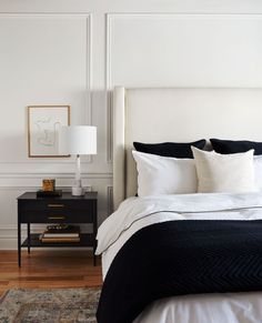 a bedroom with white walls and black bedding