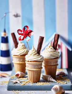 three cupcakes with white frosting and chocolate sticks sticking out of the top