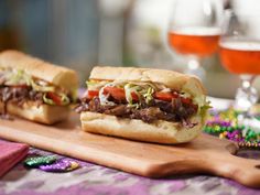 two sandwiches sitting on top of a wooden cutting board