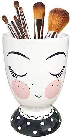 a white cup filled with lots of makeup brushes