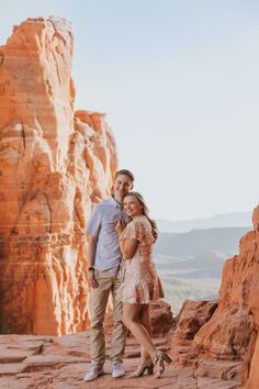 a man and woman standing on top of a rock formation