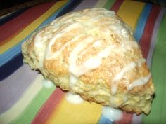 a biscuit with icing sitting on top of a colorful table cloth