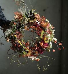 a person holding a wreath with flowers and berries