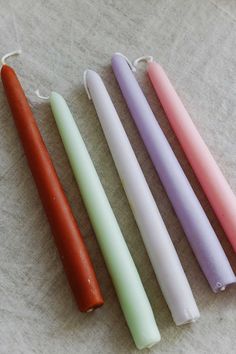 three different colored candles sitting next to each other on top of a white tablecloth