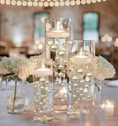 the centerpieces are filled with white flowers, candles and glass vases for an elegant touch