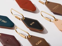 several leather luggage tags are shown on a white surface, with gold metal handles and letters that spell out the name