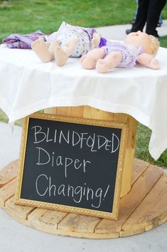 a sign that says blindfolded diaper changing on top of a wooden stand