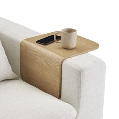 a table with a cup on top of it next to a couch and pillow in the background