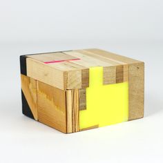 a piece of wood with yellow and black squares on it's sides, sitting in front of a white background