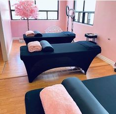 two black couches with towels on them in a living room next to pink flowers