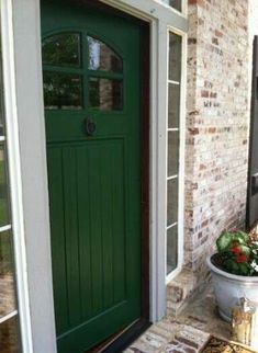 a potted plant sitting in front of a green door on the side of a brick building